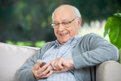 Smiling senior man reading mobile phone.
